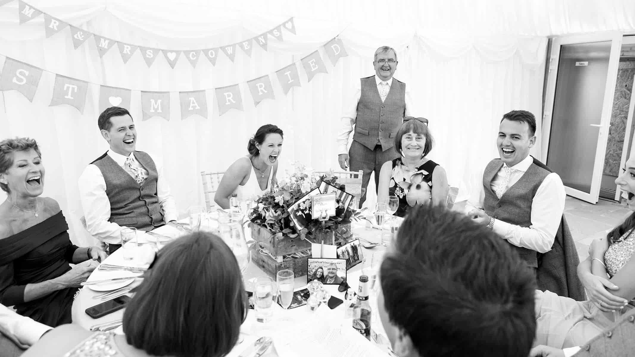 father of the bride delivering wedding speech and family laughing