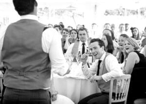 Best man delivering a wedding speech to a large audience who are all laughing. Speech delivery coaching has worked.