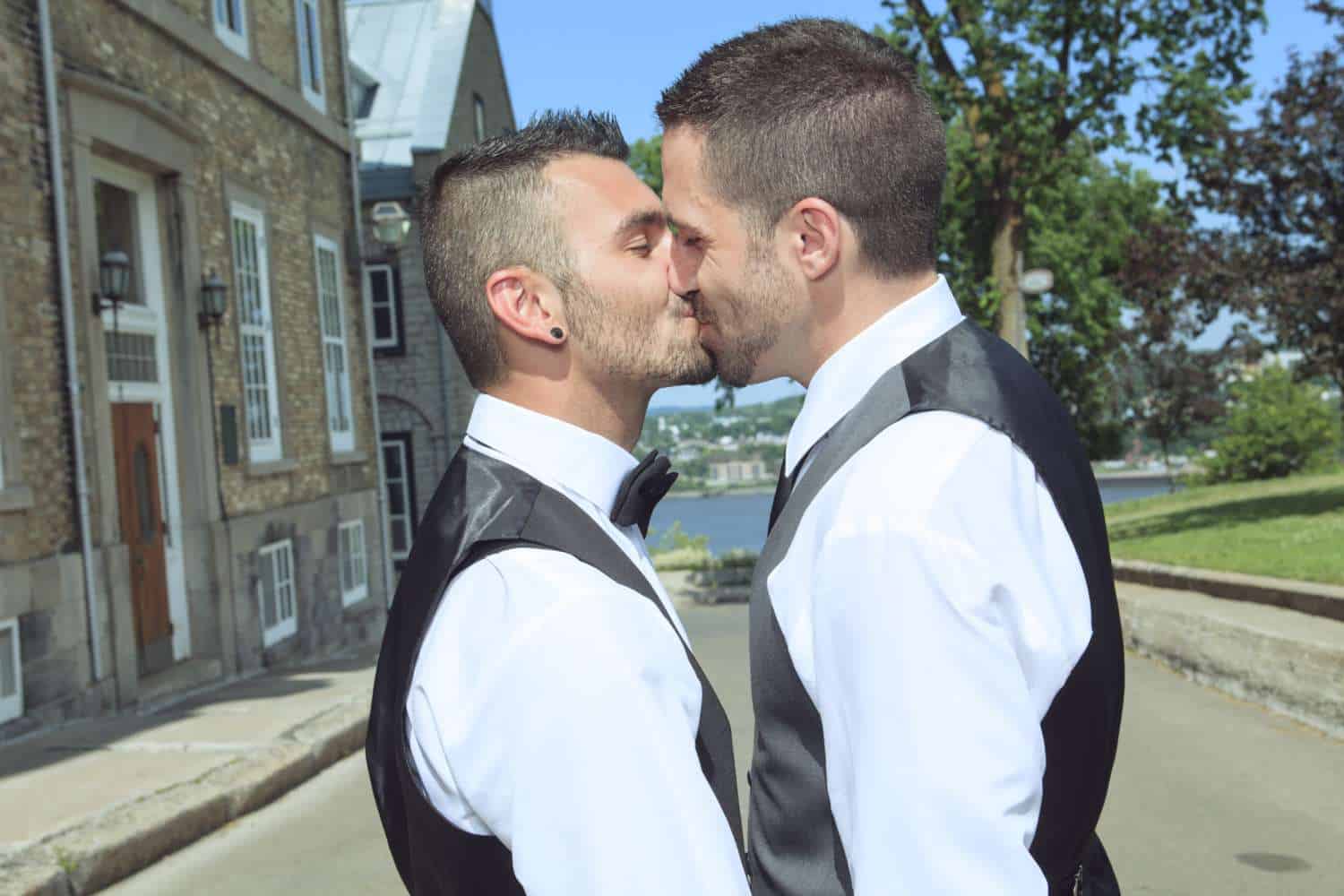 Gay grooms smiling and kissing.