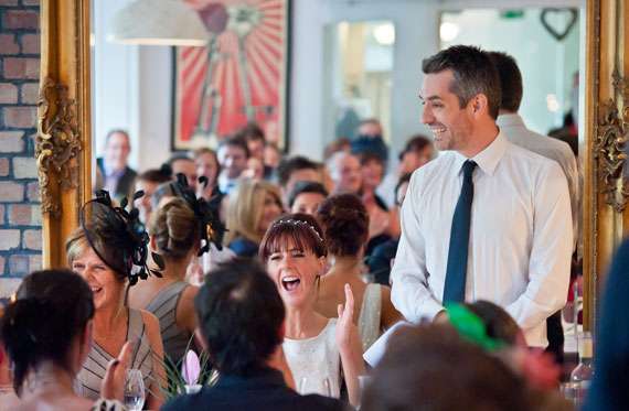 Groom delivering a rhyming wedding speech. Guests are laughing.