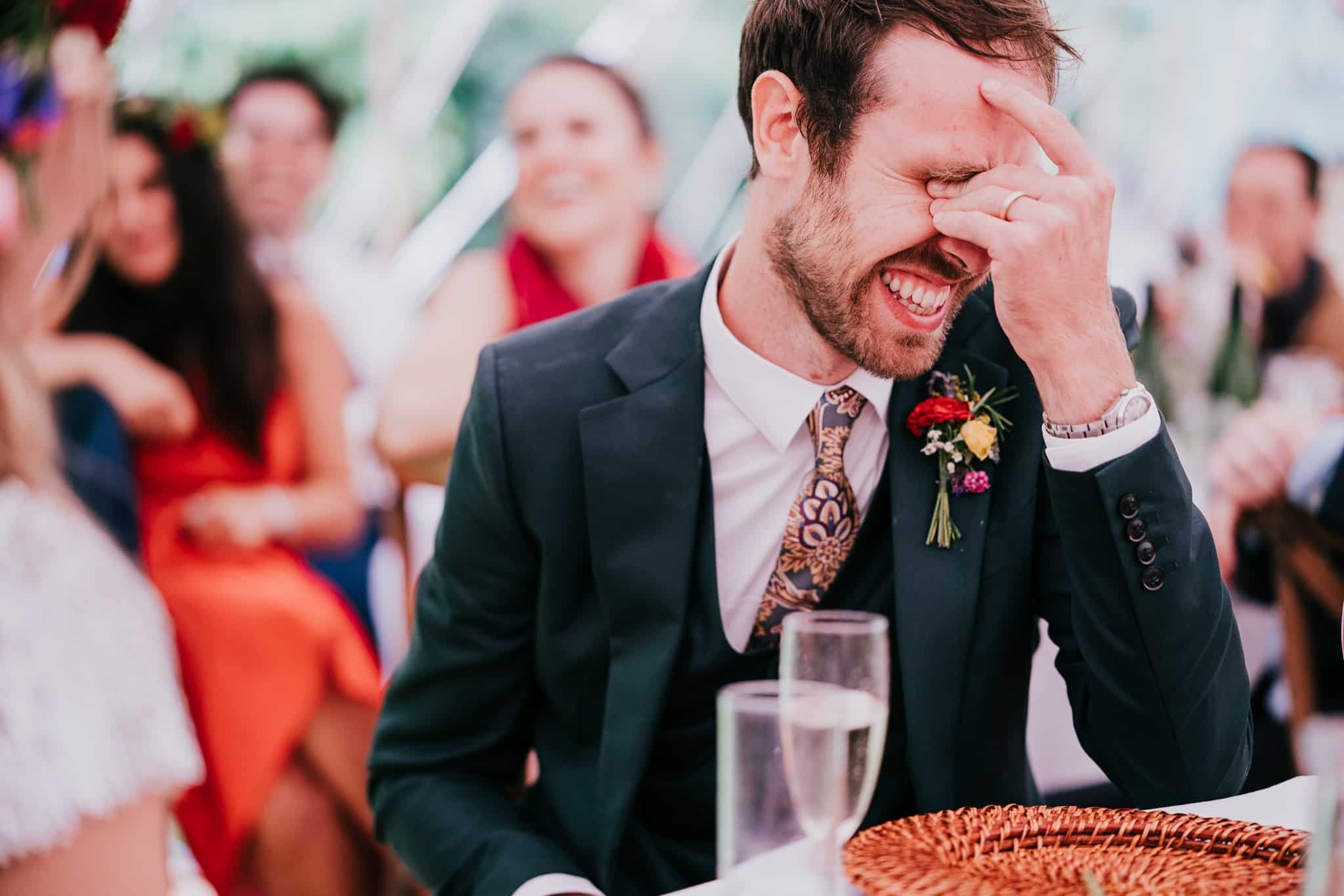 groom laughing at the wedding speech