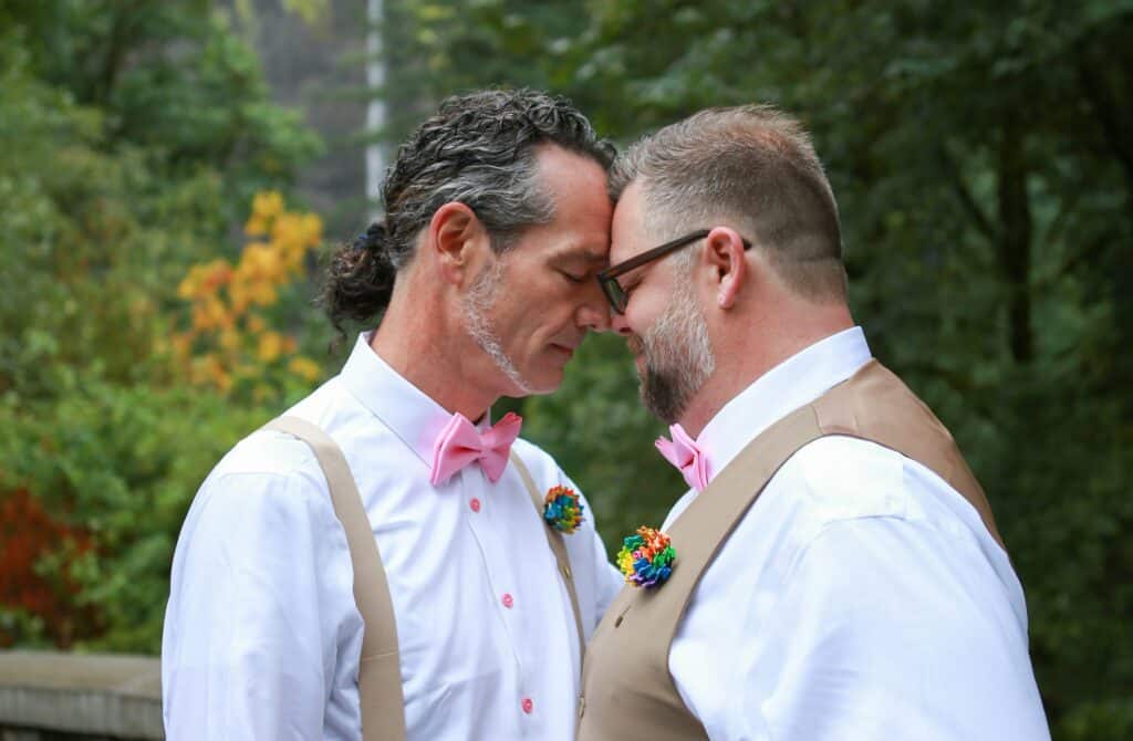 Gay grooms with heads and noses touching.